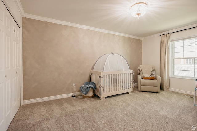 bedroom with carpet flooring, a closet, crown molding, baseboards, and a crib