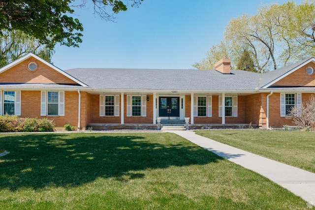ranch-style home featuring brick siding, a chimney, a front lawn, and covered porch