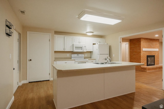 kitchen featuring white appliances, a sink, white cabinetry, and light wood-type flooring