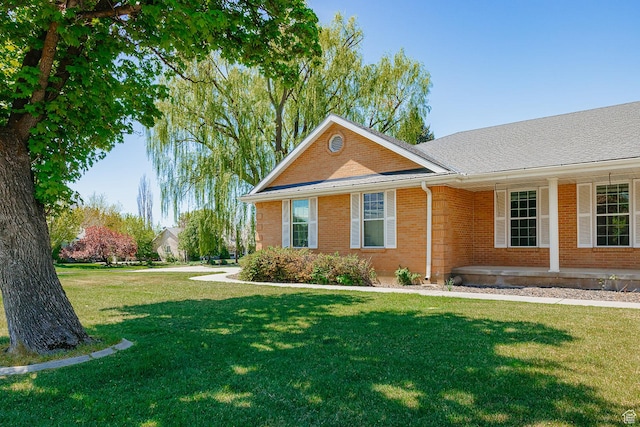 view of home's exterior featuring a yard, brick siding, and covered porch