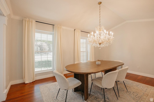 dining area featuring hardwood / wood-style flooring, a chandelier, lofted ceiling, baseboards, and ornamental molding