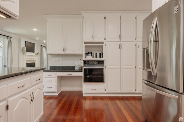 kitchen featuring stainless steel fridge, oven, dark wood finished floors, white cabinets, and dark stone countertops