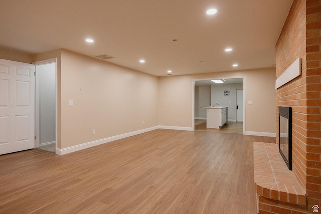 unfurnished living room featuring recessed lighting, a fireplace, light wood finished floors, and baseboards