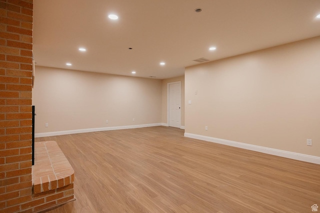 below grade area with light wood-style floors, recessed lighting, baseboards, and a fireplace