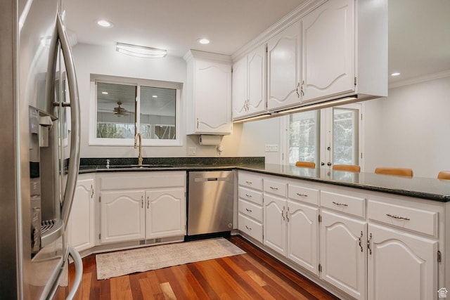 kitchen featuring stainless steel appliances, a sink, dark wood-style floors, a peninsula, and white cabinets