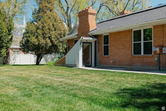 back of house with a chimney, brick siding, and a shingled roof