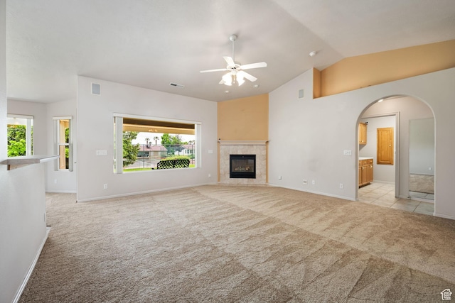unfurnished living room featuring light colored carpet, ceiling fan, healthy amount of natural light, lofted ceiling, and baseboards