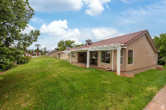 back of house with a tile roof, a lawn, a patio area, and stucco siding