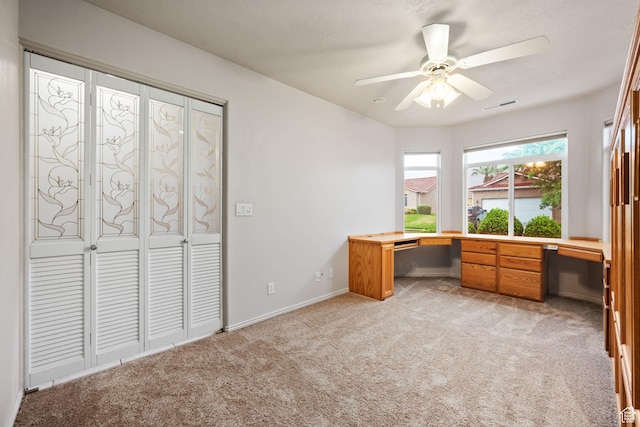 unfurnished office with light carpet, ceiling fan, and baseboards
