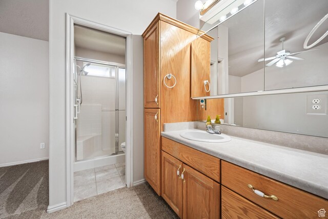 bathroom featuring ceiling fan, a stall shower, vanity, toilet, and baseboards