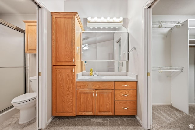bathroom with toilet, vanity, a shower with door, and baseboards