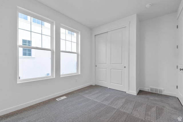 unfurnished bedroom featuring carpet floors, baseboards, and a closet