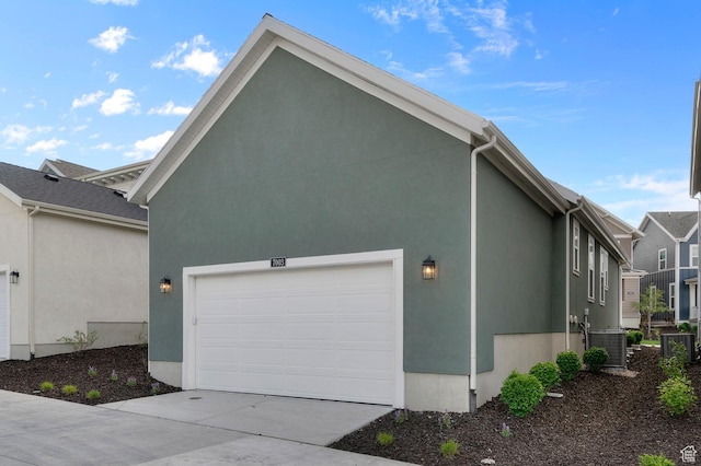 view of side of home featuring concrete driveway, a garage, central AC unit, and stucco siding