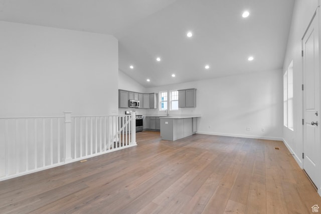 unfurnished living room with vaulted ceiling, light wood-style floors, recessed lighting, and a sink