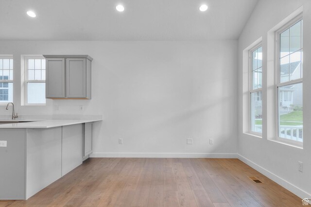 unfurnished dining area featuring plenty of natural light, light wood-type flooring, baseboards, recessed lighting, and a sink