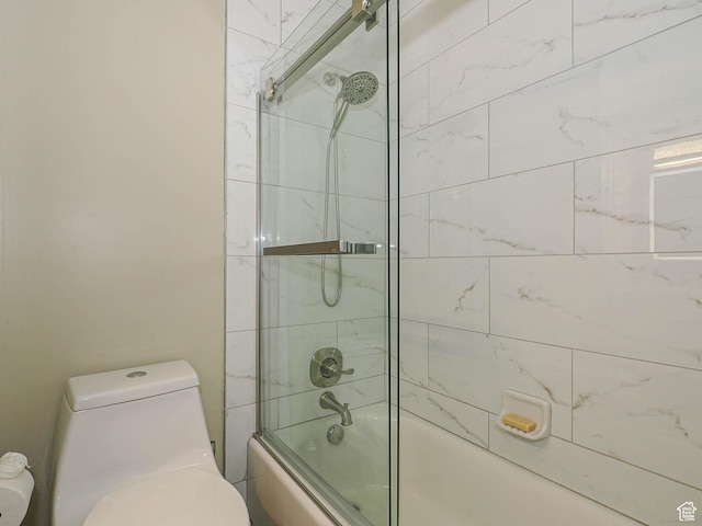 full bath featuring toilet and shower / bath combination with glass door