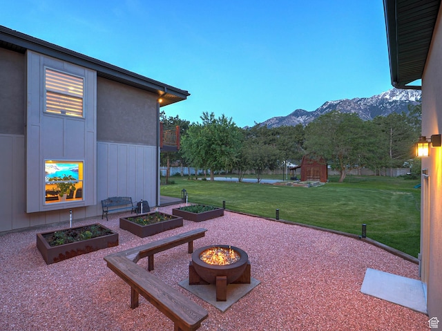 view of patio featuring a mountain view, a vegetable garden, and an outdoor fire pit