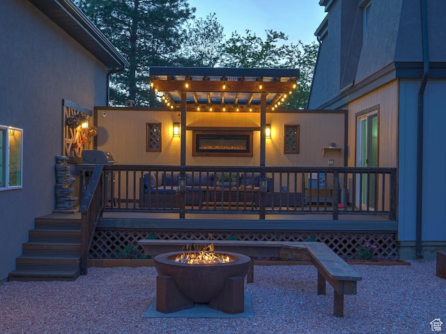 rear view of house featuring an outdoor fire pit, stucco siding, and a deck