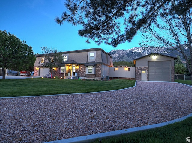 view of front of home with gravel driveway, a front lawn, a mountain view, central AC, and a garage