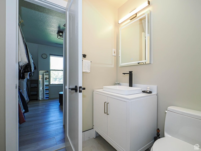 bathroom with toilet, wood finished floors, and vanity