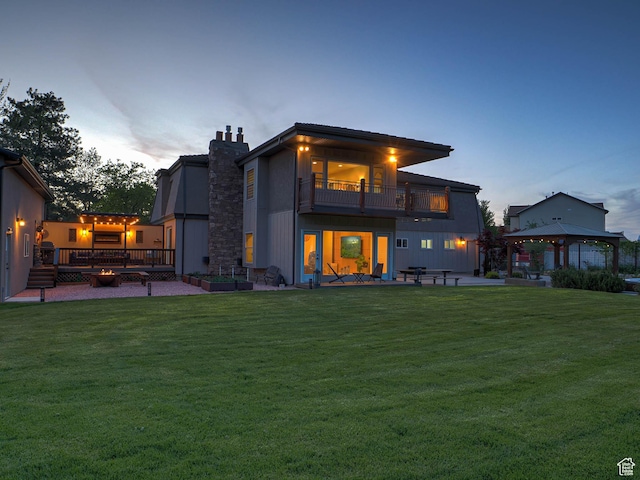 rear view of property with a balcony, a gazebo, a lawn, and a patio