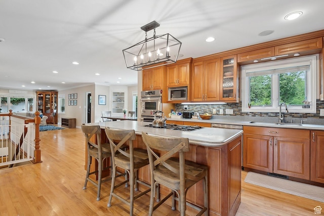 2625 E Kentucky Ave, Holladay, UT 84117 - kitchen with appliances with stainless steel finishes, a sink, brown cabinetry, a kitchen island, and backsplash