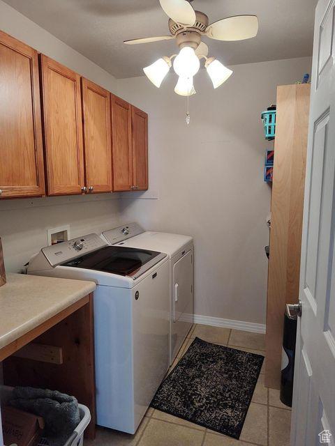 laundry room with cabinet space, washer and clothes dryer, a ceiling fan, light tile patterned flooring, and baseboards