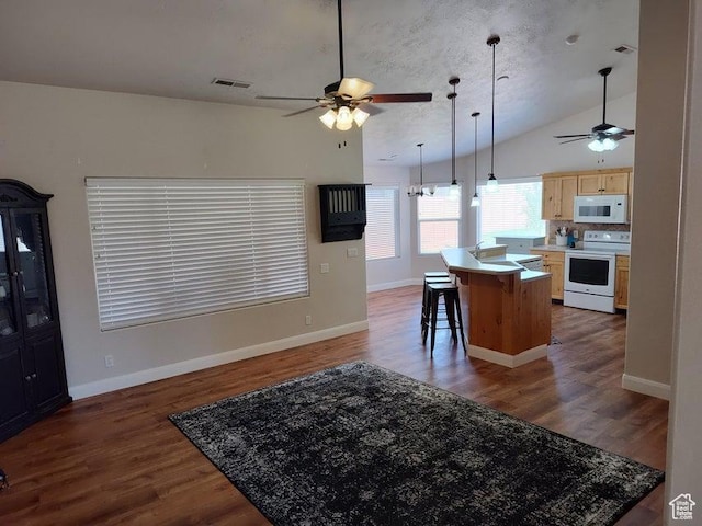 kitchen with white appliances, a ceiling fan, light brown cabinetry, vaulted ceiling, and open floor plan