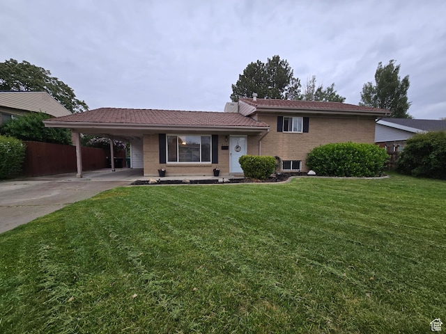 tri-level home featuring driveway, an attached carport, a tile roof, and brick siding