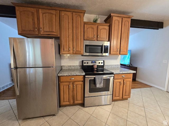 614 W Anderson Ave S, Murray, UT 84123 - kitchen with stainless steel appliances, tasteful backsplash, brown cabinets, light tile patterned floors, and light stone counters