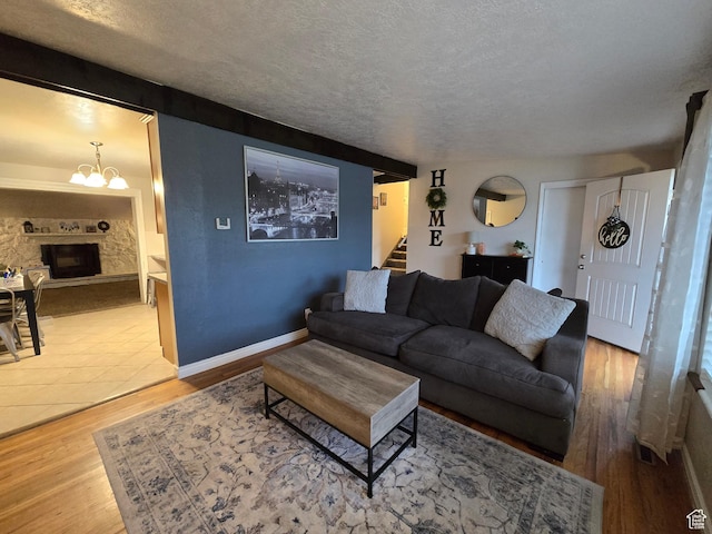 living room featuring stairway, wood finished floors, a chandelier, a textured ceiling, and baseboards