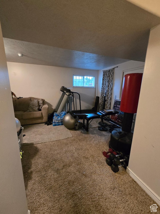 workout area with a textured ceiling, carpet flooring, and baseboards