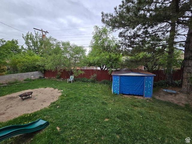 view of yard with a storage unit, an outdoor structure, and an outdoor fire pit