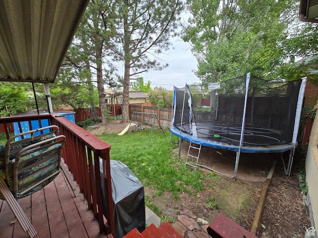 view of yard with a trampoline and a wooden deck