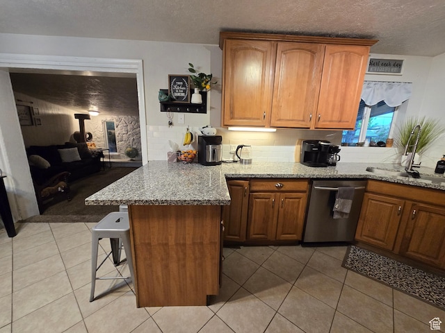 kitchen with stainless steel dishwasher, backsplash, light stone countertops, a kitchen breakfast bar, and a peninsula