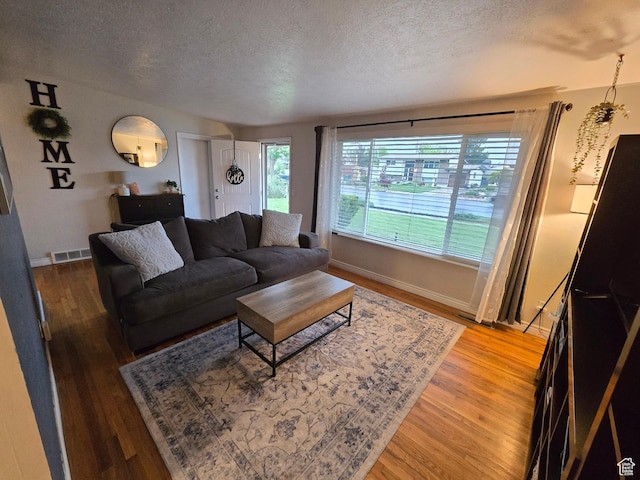 living area with a textured ceiling, wood finished floors, and baseboards