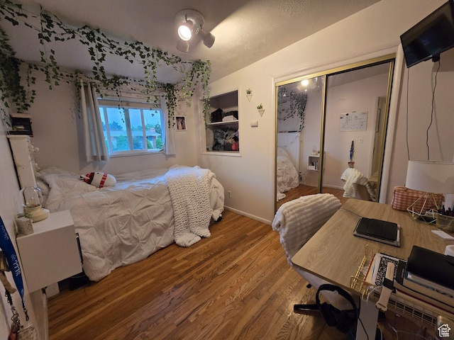 bedroom featuring wood finished floors, a closet, and baseboards