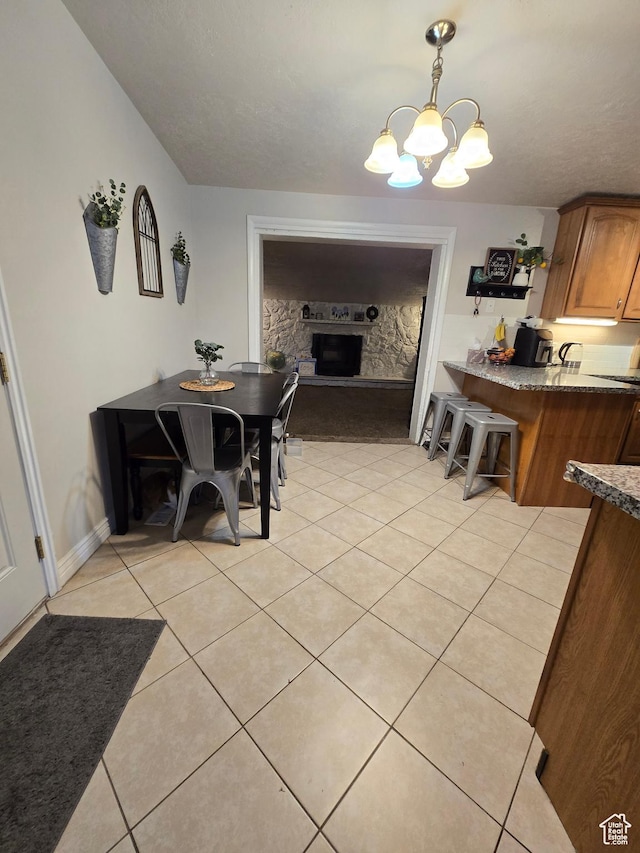 dining room featuring a chandelier, light tile patterned floors, a fireplace, and baseboards