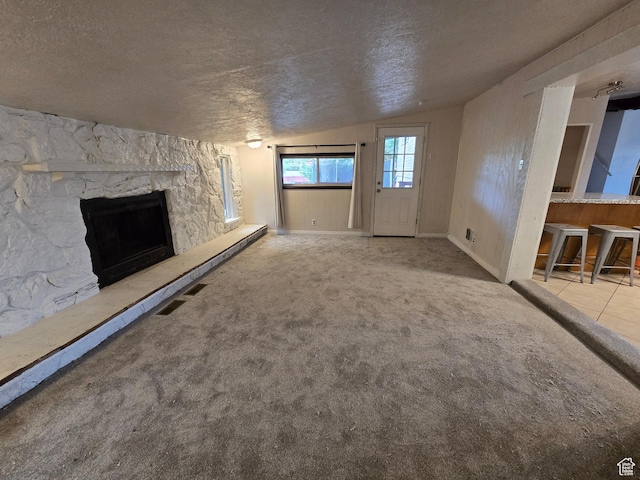 614 W Anderson Ave S, Murray, UT 84123 - unfurnished living room featuring a textured ceiling, lofted ceiling, a stone fireplace, and carpet