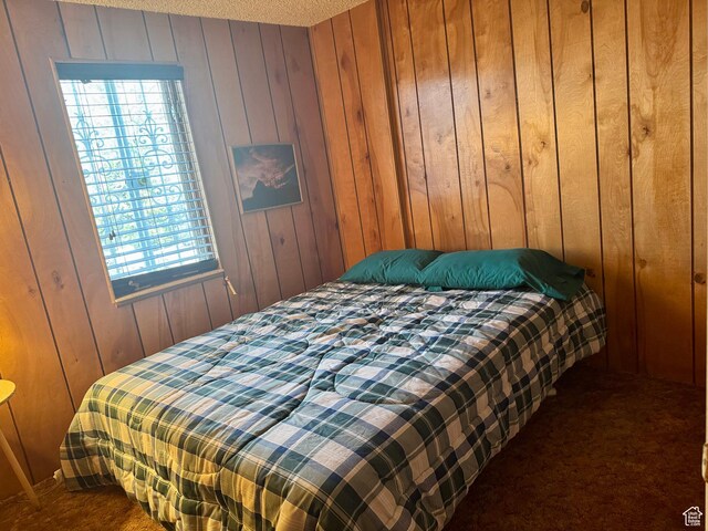 bedroom featuring dark carpet, wooden walls, and multiple windows