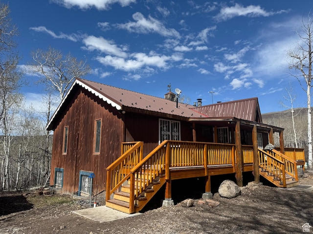 rear view of house featuring a deck, metal roof, and stairs