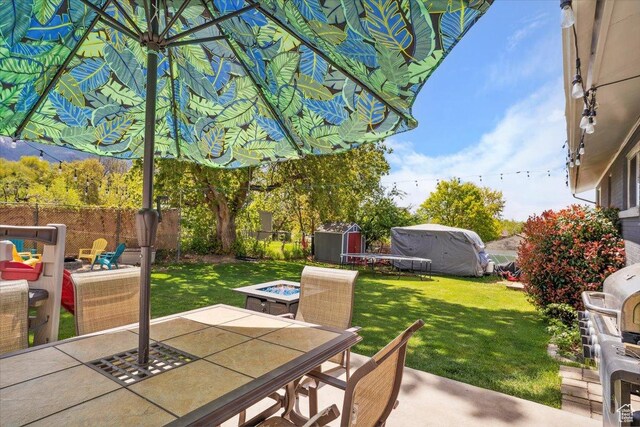 2884 N 300 E, North Ogden, UT 84414 - view of patio / terrace featuring outdoor dining space, a shed, an outdoor structure, and an outdoor fire pit