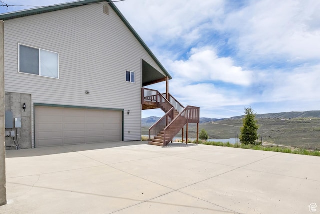 view of side of property featuring a garage, stairs, a mountain view, and driveway