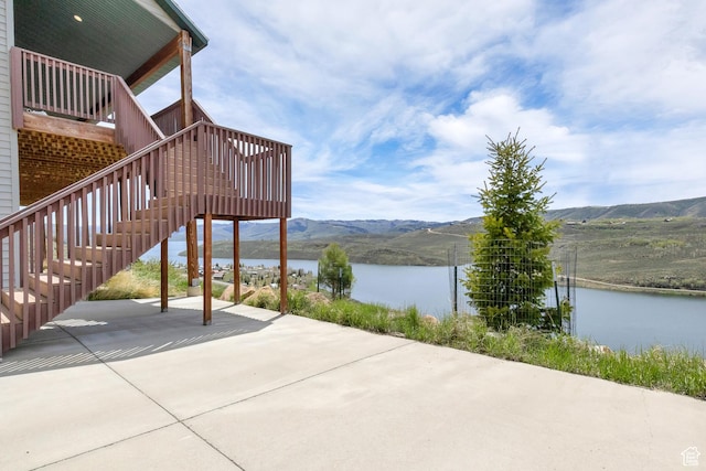 view of patio featuring a water and mountain view and stairs