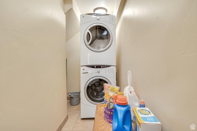 laundry area with stacked washer / drying machine and light tile patterned flooring