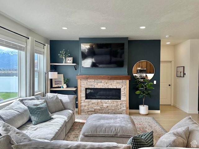 living area with wood finished floors, a fireplace, a textured ceiling, recessed lighting, and baseboards