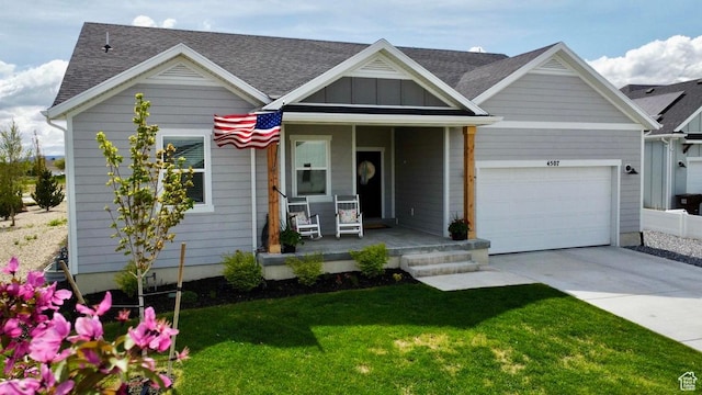 view of front of property featuring covered porch, concrete driveway, a garage, a front yard, and a shingled roof