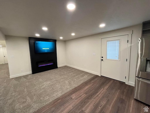 unfurnished living room featuring dark wood-style flooring, recessed lighting, baseboards, and a fireplace