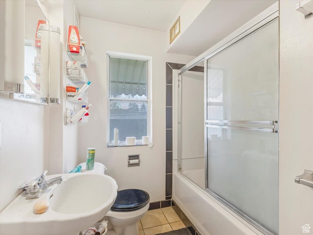 bathroom featuring tile patterned flooring, a sink, toilet, and enclosed tub / shower combo