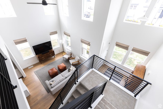 living room with a towering ceiling, wood finished floors, a ceiling fan, and baseboards